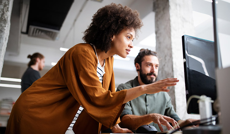 Two Coworkers Looking At Laptop